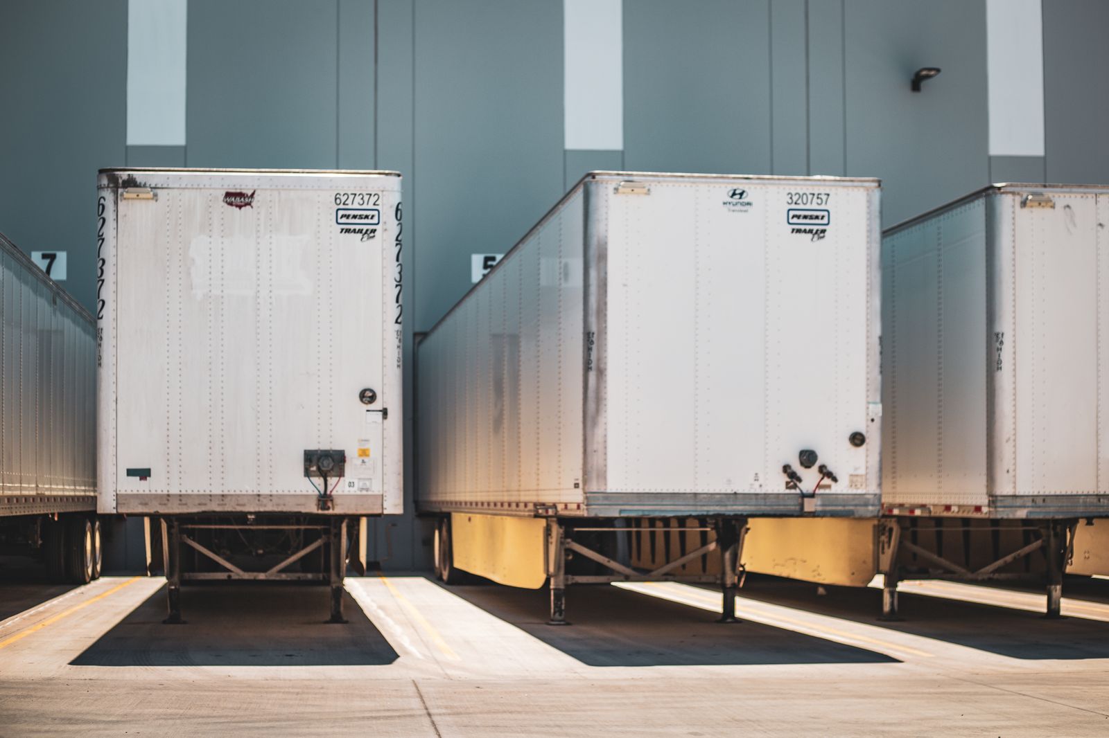 Dry van trailers backed into numbered dock doors at a warehouse, no tractors attached